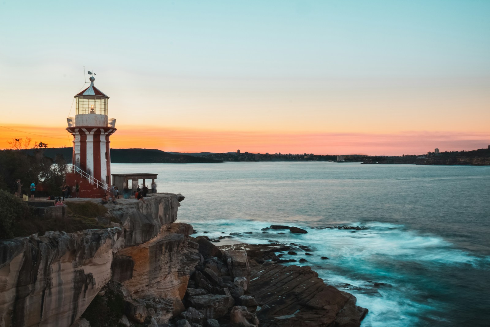a red and white lighthouse sitting on top of a cliff next to the ocean